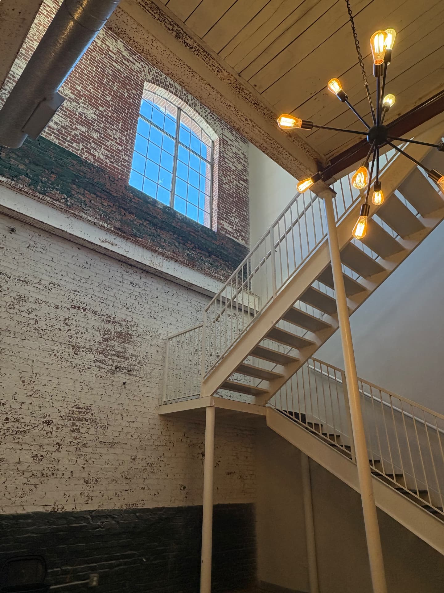 Exposed brick stairwell with an industrial chandelier